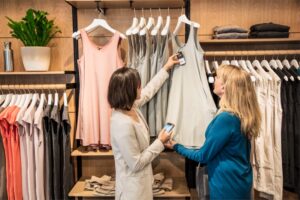 Store employee helping customer purchase clothing.